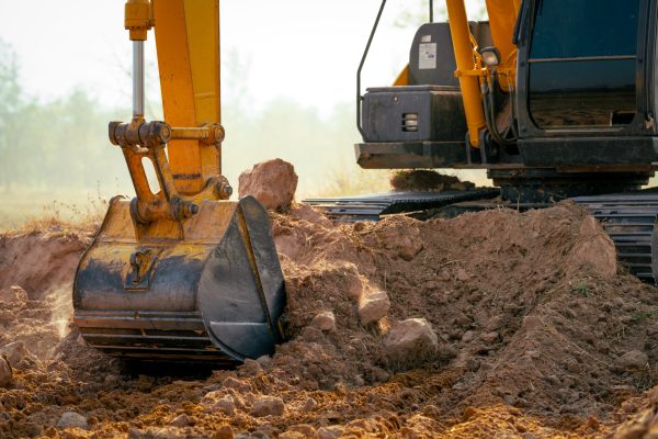 Closeup bucket of backhoe digging the soil at construction site. Crawler excavator digging on demolition site. Excavating machine. Earth moving equipment. Excavation vehicle. Construction business.